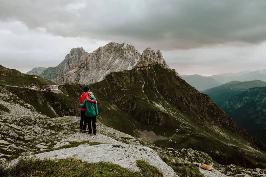 Couple standing on a mountain top looking out at the mountains