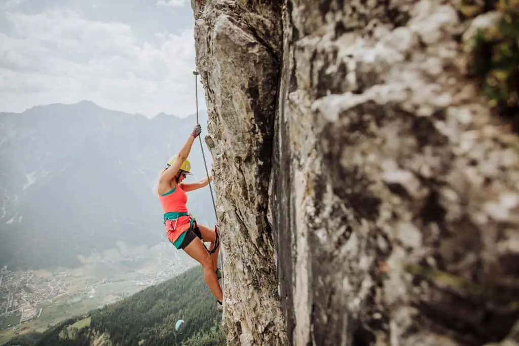 Blonde woman on a via ferrata cliff edge in the Austrian Alps