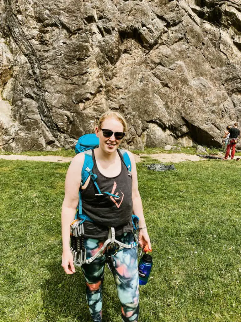 Woman standing at the bottom of a rock climbing wall in colourful leggings