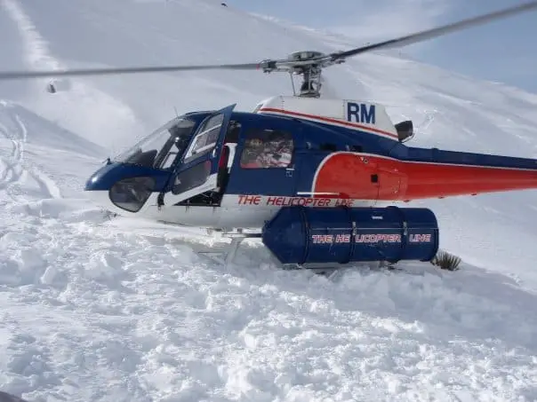 Helicopter landing on the snow to drop of skiers in New Zealand