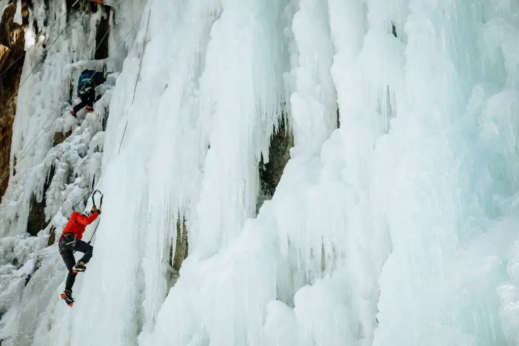 Man in a red jacket climbing an ice waterfall