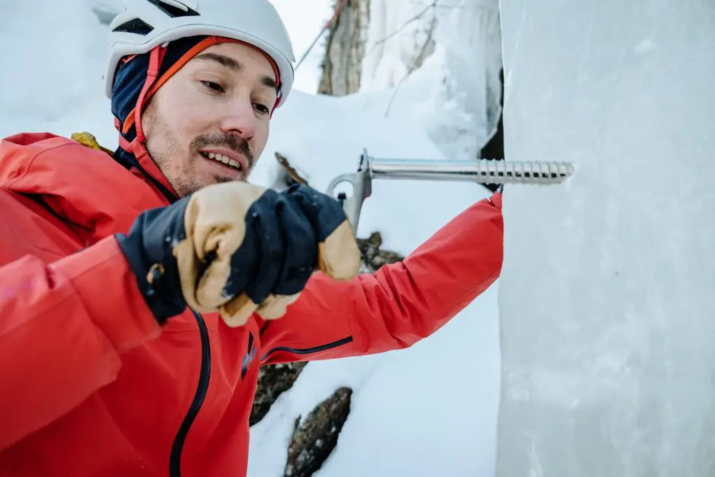 Man placing an ice screw in a wall of ice for climbing