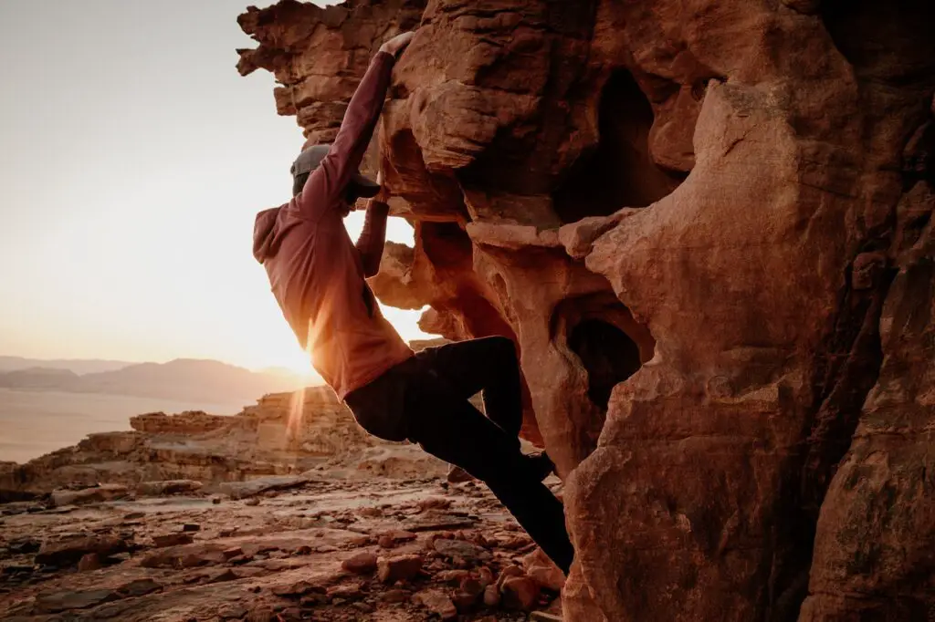 A man in a red top rock climbing in Jordan