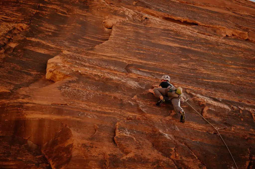 Man in black t-shirt climbing on the red sandstone walls of Wadi Rum in Jordan