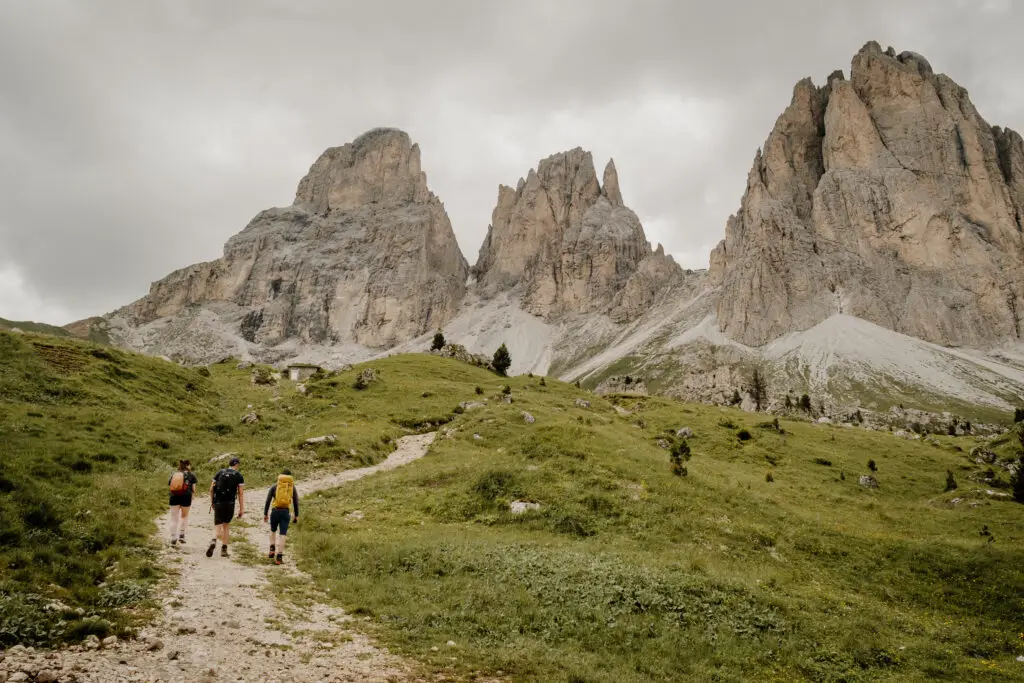 3 hikers on a hiking trail under the Sassolungo in the Dolomites