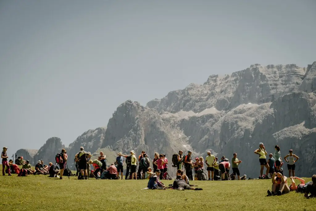 A photo showing a large crowd of around 50 hikers all standing in a meadow on the Sella Pass in the Dolomites